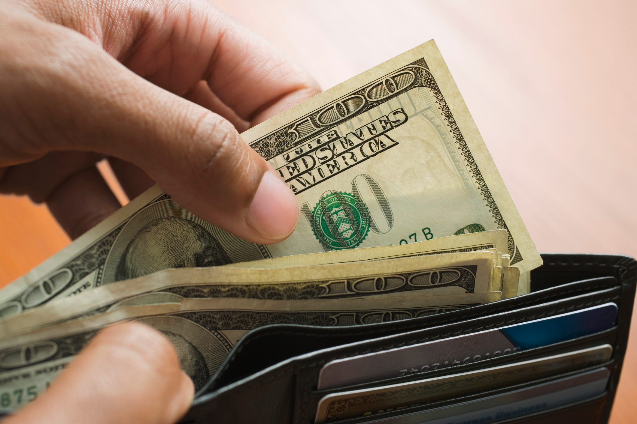 close up of person taking cash out of wallet