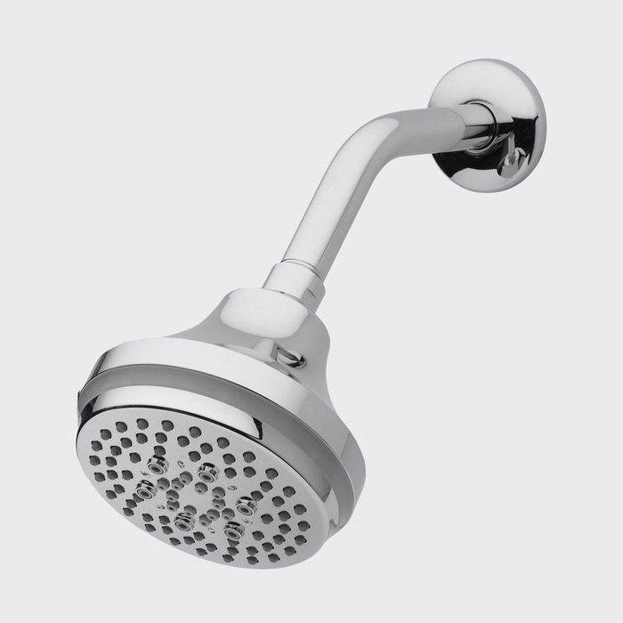 A chrome showerhead is mounted on a wall, positioned to dispense water. The sleek design features a round face with multiple holes for water flow.