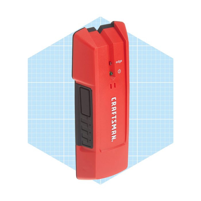 A red Craftsman tool with buttons and indicators is positioned on a light blue grid background, indicating it may be a measuring or testing device.
