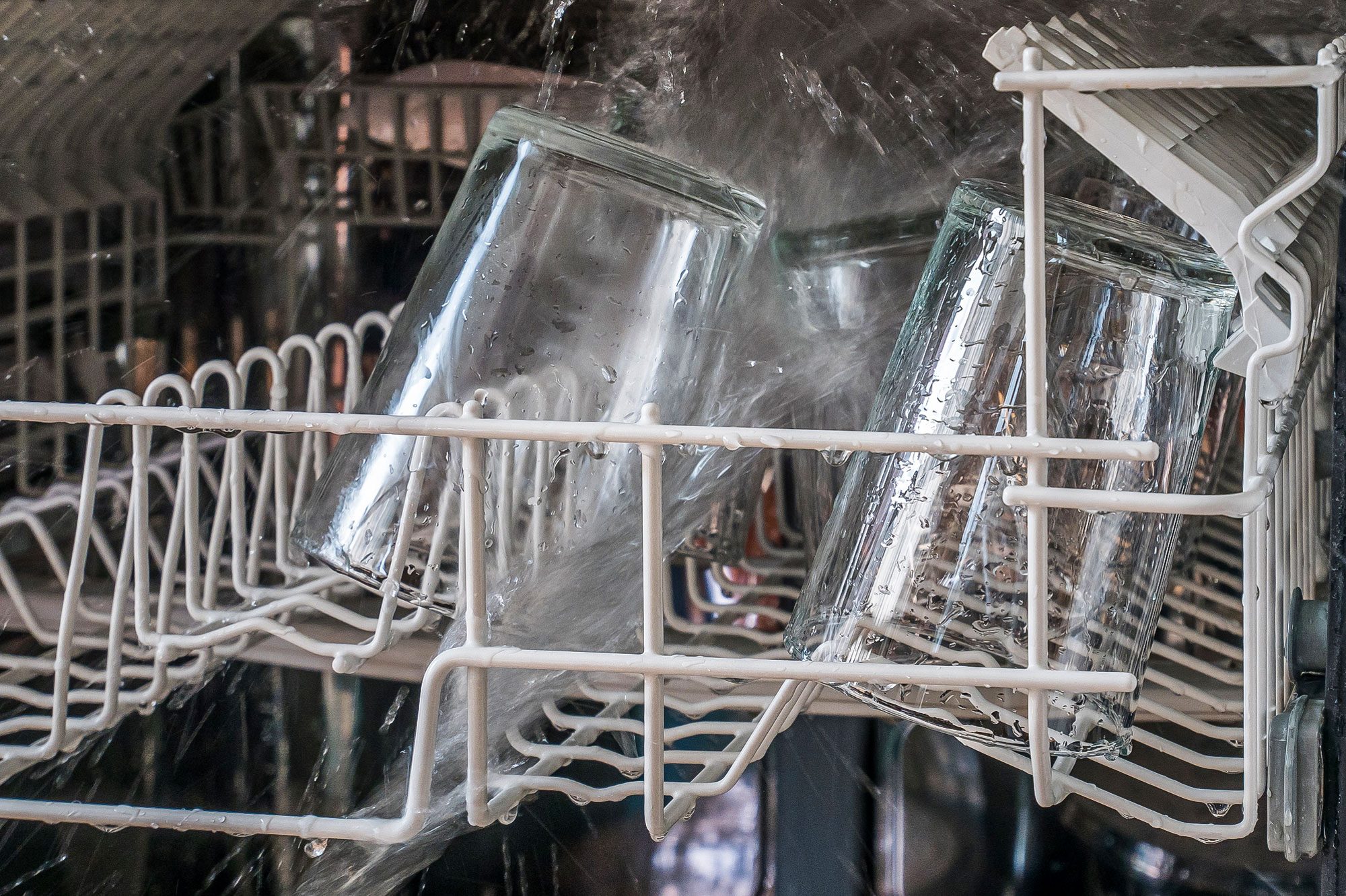 Open Dishwasher Machine Spraying Water On Drinking Glass